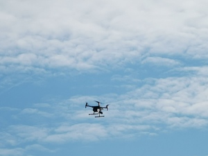 zdjęcie kolorowe: latający dron i fragment nieba