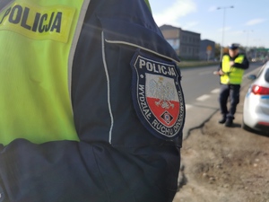 na zdjęciu widać fragment naszywki, w tle drugiego policjanta drogówki