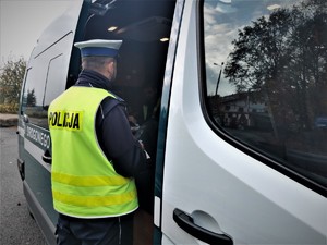 Policjant drogówki stoi przy samochodzie Inspektoratu Transportu Drogowego i rozmawia z funckjonariuszami