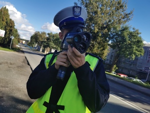 policjant drogówki dokonuje pomiaru prędkości ręcznym miernikiem