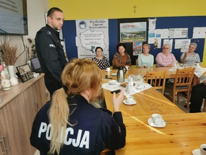 spotkanie policjantów z seniorami w miejscowości Gostyń, wszyscy siedzą przy stole, policjant - prelegent przemawia