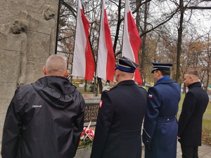 delegacja władz powiatu oddaje hołd poległym, w tle widać trzy flagi biało-czerwone