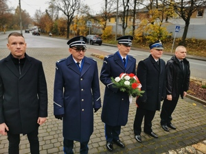 delegacja władz, wśród nich policjanci, którzy trzymają kwiaty