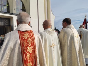 trzech księży stoi przed budynkiem kościoła