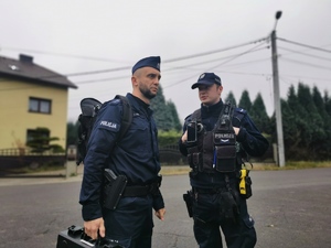 na zdjęciu widać dwóch policjantów prewencji przed budynkiem komisariatu w Orzeszu