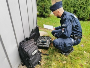 na zdjęciu policjant pirotechnik kuca przy podejrzanym pakunku