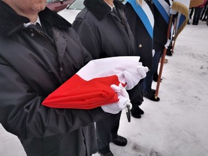 na zdjęciu widać złożoną flagę Polski trzymaną przez strażaka-ochotnika