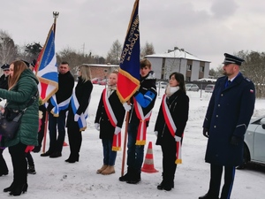 na zdjęciu widać uczniów trzymających sztandar gminy oraz policjanta w mundurze galowym