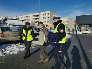 na zdjęciu policjanci wręczający przechodniom odblaskowe opaski