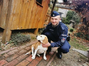 na zdjęciu widać policjanta, który kuca przy psie