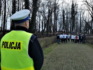 na zdjęciu widać policjanta drogówki, w tle uczestnicy biegu pod pomnikiem w Mikołowie