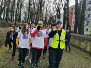 na zdjęciu widać uczestników biegu, którzy szykują się do dalszej trasy. Jeden z nich rozmawia z policjantem drogówki