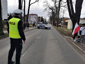 na zdjęciu policjant drogówki w odblaskowej kamizelce, który zabezpiecza trasę biegu w centrum Mikołowa