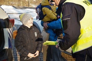 na zdjęciu policjant drogówki przekazuje odblaskową opaskę małemu chłopcu, który uśmiecha się szeroko