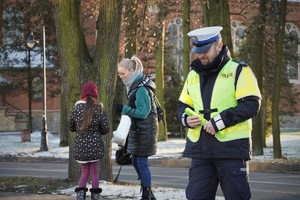 na zdjęciu wykonanym w centrum Ornontowic widać policjanta w odblaskowej kamizelce, tuż za nim kobieta