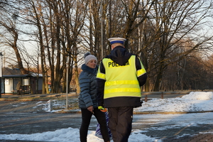 na zdjęciu widać policjanta drogówki, który przekazuje odblask starszej kobiecie