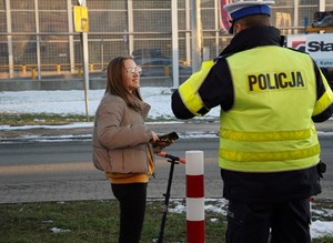 na zdjęciu widać policjanta drogówki, który przekazuje osobie odblask. Scena ma miejsce w Orzeszu-Gardawicach