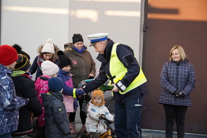 policjant drogówki rozdaje ludziom odblaskowe opaski