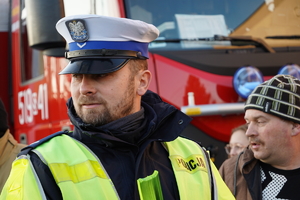 policjant drogówki,  obok niego mężczyzna, w tle samochód straży pożarnej