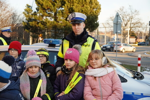 policjant drogówki pozuje do zdjęcia z grupą osób, w tle policyjny radiowóz