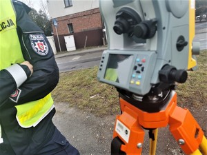 na zdjęciu policjant drogówki stoi obok tachimetru