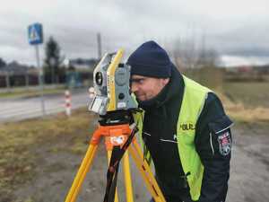 policjant mikołowskiej drogówki patrzy przez wizjer tachimetra