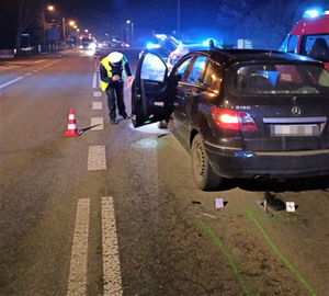 na zdjęciu widać policjanta drogówki, który sporządza dokumentację po wypadku, obok niego stoi czarny samochód