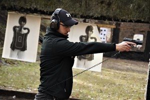 na zdjęciu widać instruktora strzelania, który objaśnia sposób wydobywania broni z kabury