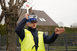 na zdjęciu policjant drogówki z podniesionymi do góry rękoma w trakcie zatrzymywania pojazdu