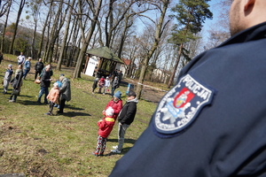 komendant Policji przygląda się dzieciom biegającym po parku