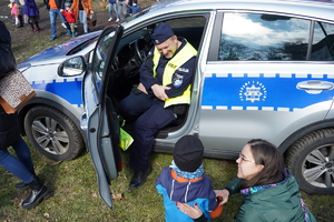 policyjny radiowóz, w środku którego siedzi policjant i rozmawia z małym dzieckiem