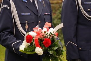 policjant trzymający w ręce wiązankę kwiatów