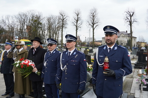 policjanci w mundurach galowych oraz pozostali mundurowi i przedstawiciele samorządu stoją  w rzędzie na cmentarzu w Ornontowicach