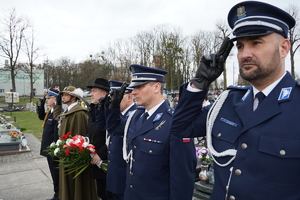 policjanci w mundurach galowych oraz pozostali mundurowi i przedstawiciele samorządu stoją  w rzędzie na cmentarzu w Ornontowicach