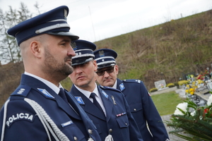 zdjęcie przedstawia trzech policjantów w mundurach galowych, którzy stoją na cmentarzu