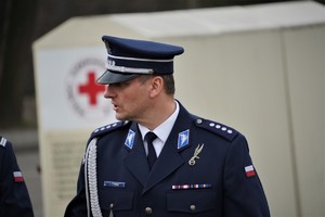Komendant w mundurze galowym, w tle czerwony krzyż