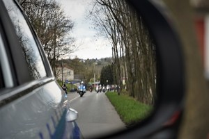 zdjęcie wykonane z wnętrza radiowozu. W lusterku odbija się parada motocyklistów