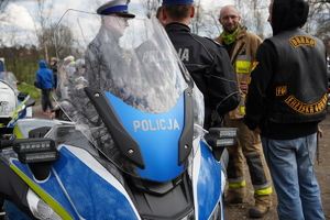 policyjny motocykl, tuż za nim policjant który rozmawia z uczestnikami parady