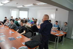 na zdjęciu widać policjanta, który przemawia do grupy uczniów. Scena ma miejsce na auli w budynku komendy w Mikołowie