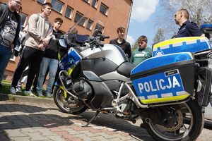 uczniowie ustawieni w półkole stoją przed budynkiem komendy i oglądają motocykl marki BMW