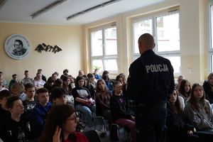 na zdjęciu widać policjanta, który rozmawia z uczniami w sali konferencyjnej szkoły