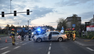 na zdjęciu widać fragment skrzyżowani z sygnalizacją świetlną, rozbite BMW, w tle służby, w tym straż pożarna