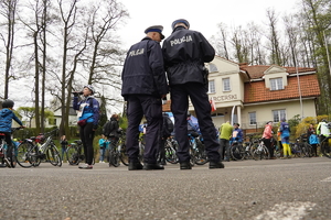 zdjęcie wykonane z oddali, stoją policjanci, patrzą na grupę rowerzystów