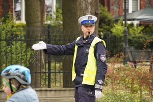 policjant drogówki kieruje ruchem, w tle rowerzysta