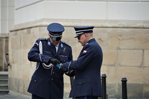 policjanci w mundurach wyjściowych zapalają znicz