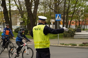 na zdjęciu policjant kierujący ruchem, zabezpiecza przejazd rowerzystów