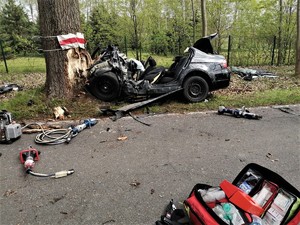 na zdjęciu widać rozbite o drzewo auto, fragmenty karoserii leżą na jezdni
