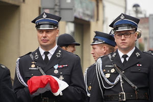 strażacy w mundurach galowych maszerują w pochodzie ulicami miasta