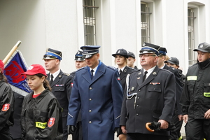 przemarsz uczestników obchodów święta strażaka. Mundurowi idą jedną z ulic miasta. Wśród nich komendant Policji