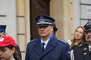 zdjęcie przedstawia maszerującego policjanta w mundurze galowym